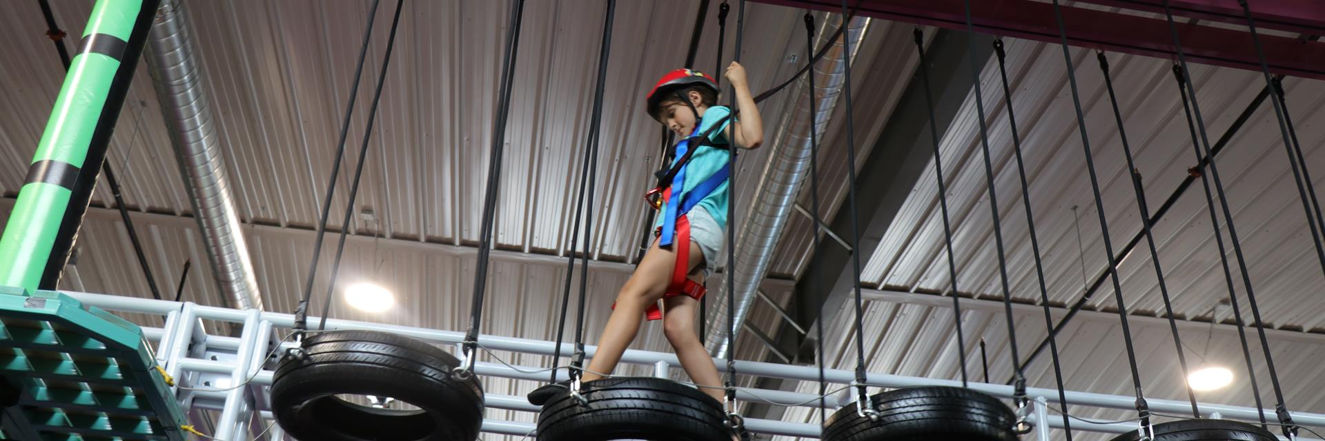 girl walking on tire bridge in indoor playground